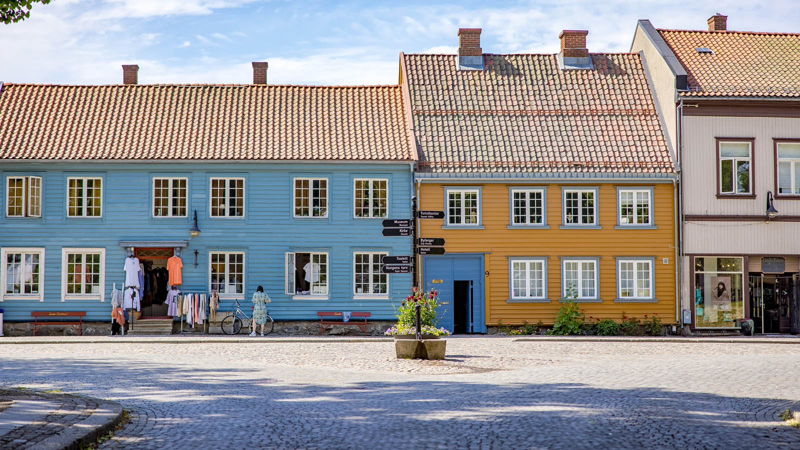 Fargerike trehus i Gamlebyen Fredrikstad, med butikker og brostein foran.