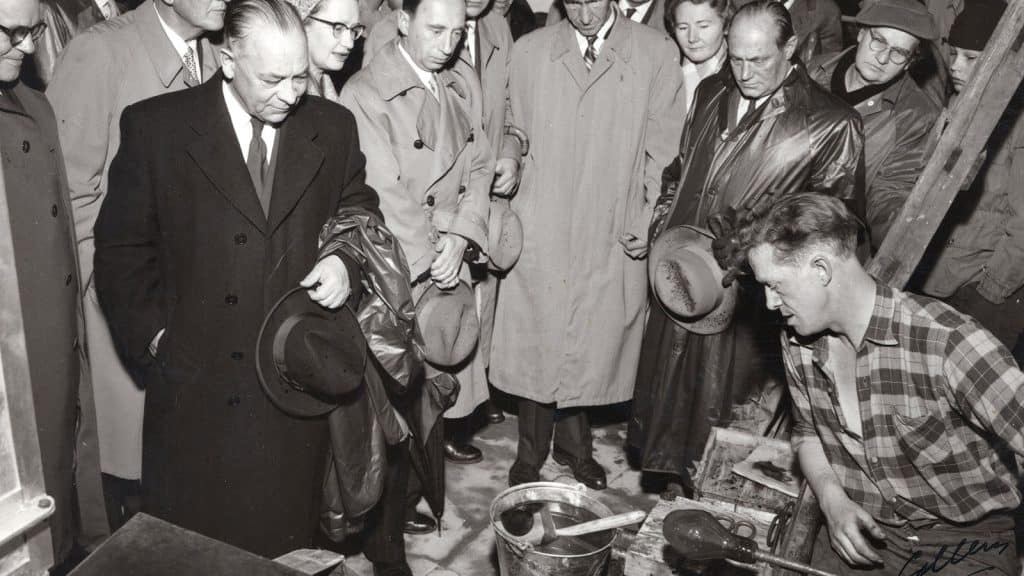 Svart-hvitt-foto av publikum som ser på glassblåsing i Gamlebyen på 1950-tallet.