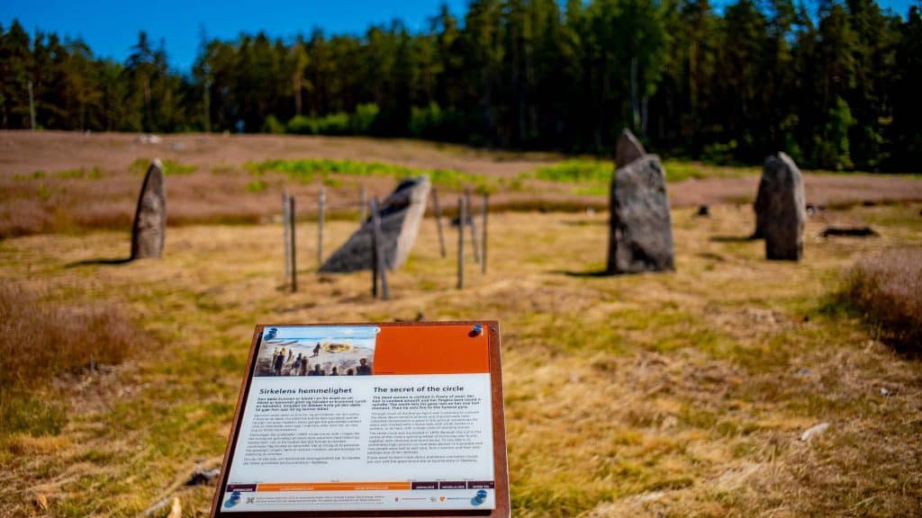 Gravfelt på Opstad i Sarpsborg, steiner i ringformasjon med informasjonsskilt i fokus.