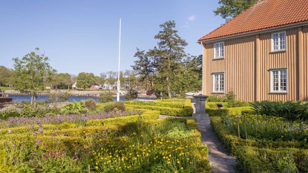 Blomstrende renessansehage med symmetriske bed og historisk bygning på Isegran i Fredrikstad.