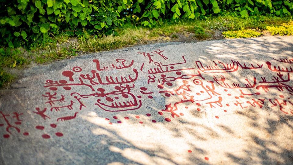 Helleristninger på Solbergfeltet, figurer i rød farge på fjell.