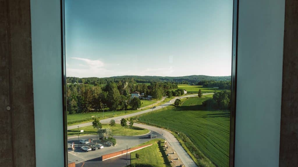 Utsikt fra Solbergtårnet mot kulturlandskapet i Østfold, med grønne jorder, skog og veier.