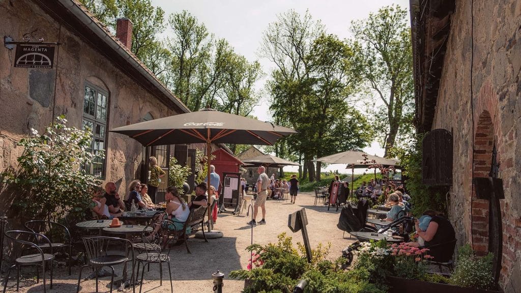 Folk nyter mat og drikke på uteservering ved Café Magenta i Gamlebyen