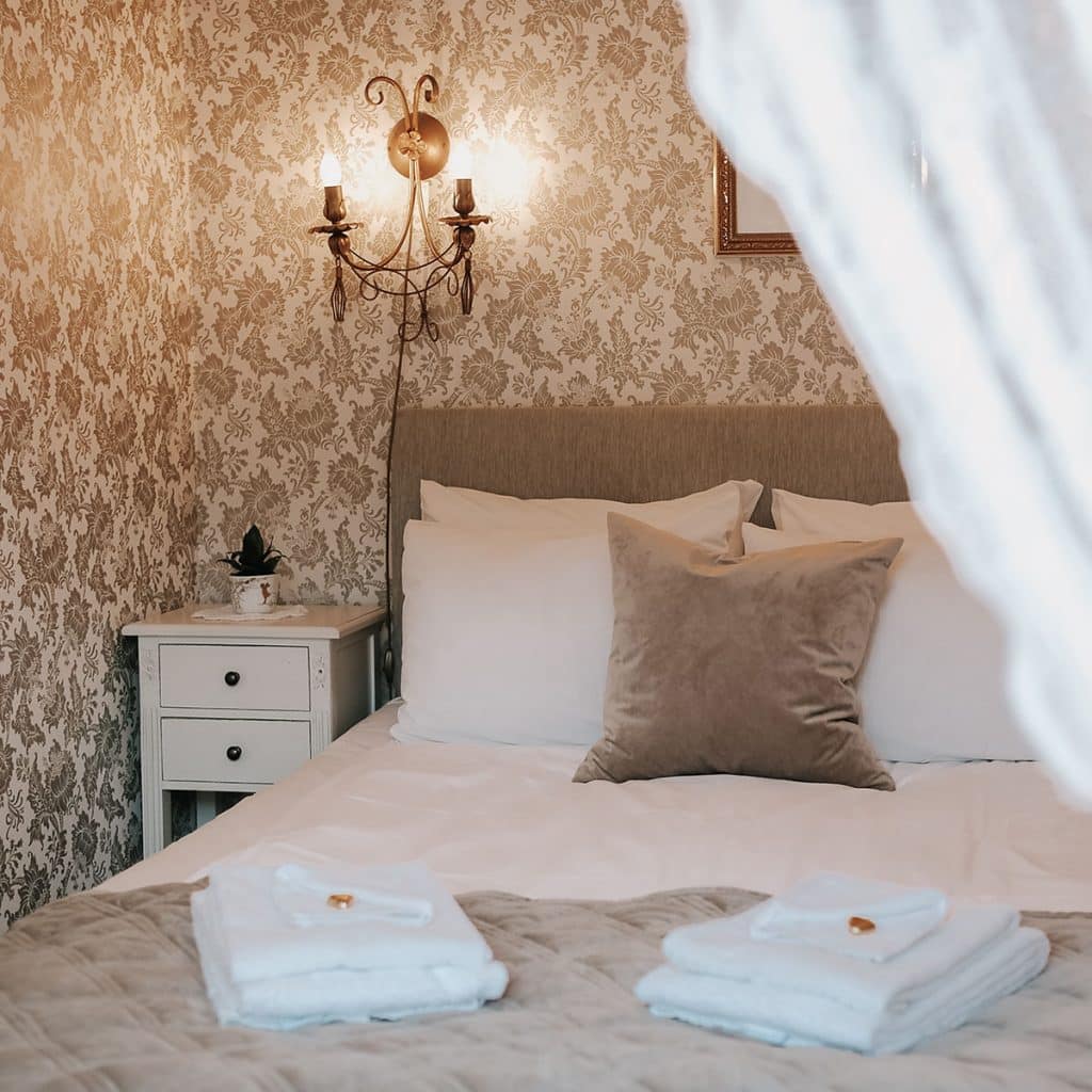 Seng med lyse tekstiler og nostalgisk tapet i Gamlebyen Hotell