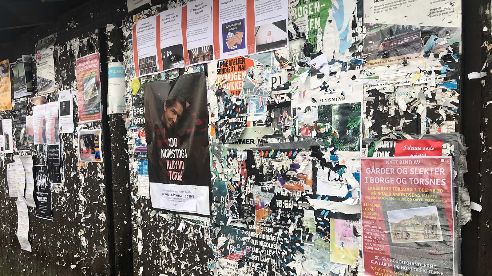 Nærbilde av overfylt plakatvegg med arrangementer, konserter og kulturplakater i Fredrikstad.