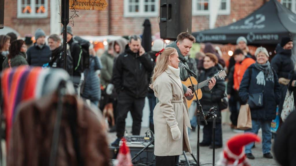 Musikere opptrer utendørs foran publikum på julemarked i Gamlebyen Fredrikstad.