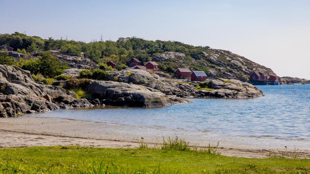 Kuvauen med strand, sjøboder og svaberg langs bukta.