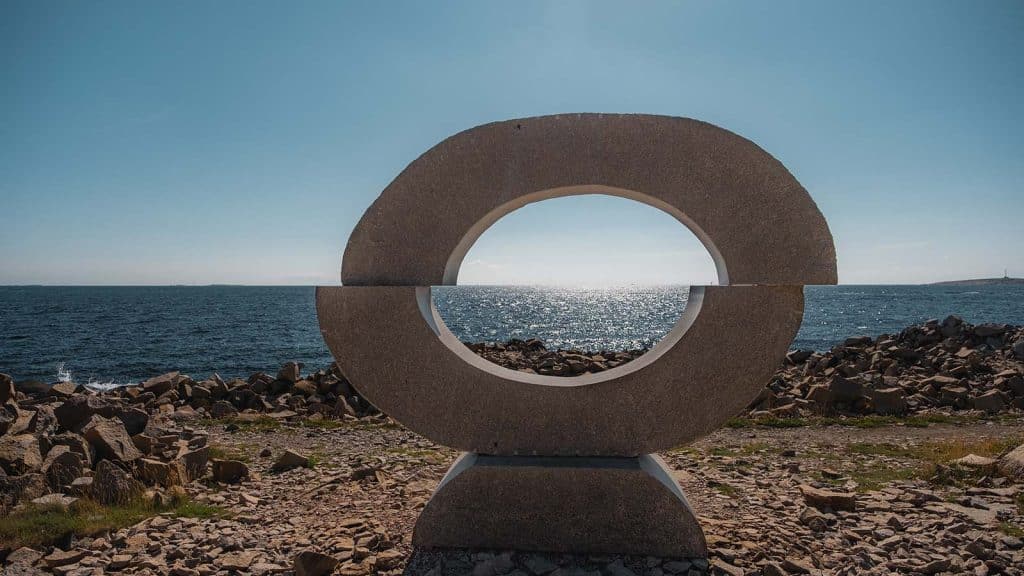 Rund steinskulptur med åpning i midten rammer inn horisonten over havet på Rødshue.