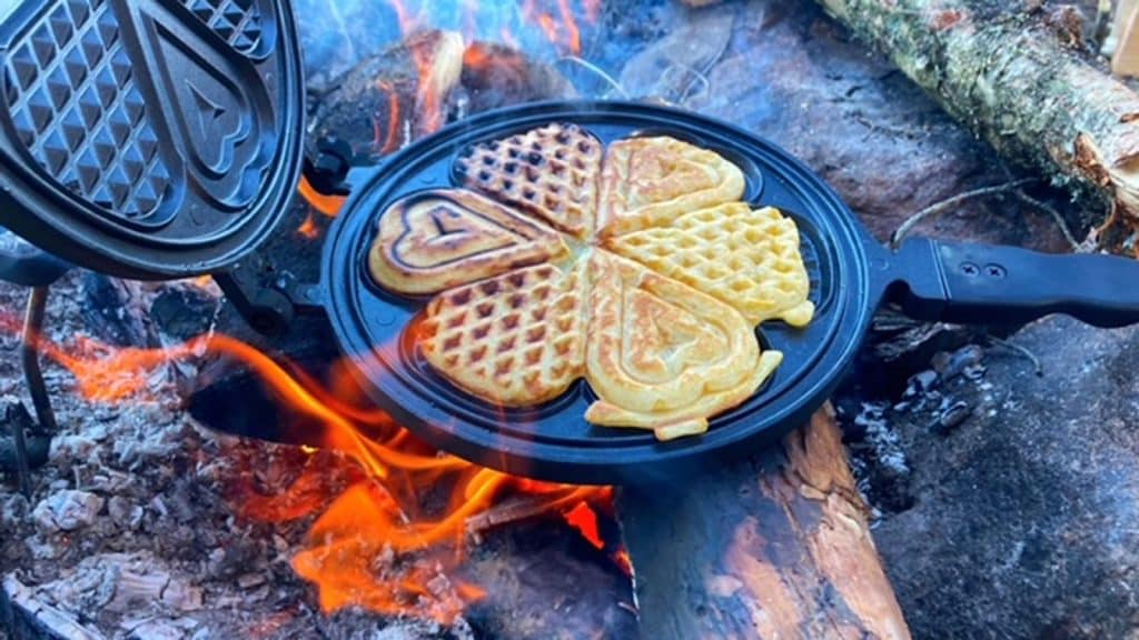 Hjertevafler stekes på bål i jernpanne.