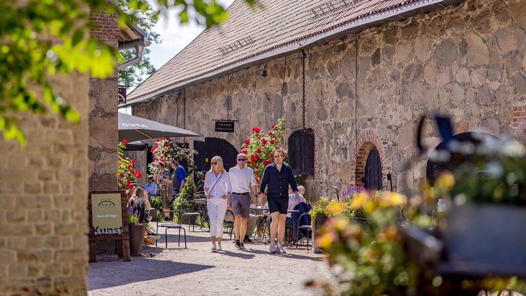 Folk rusler forbi kunstgalleri og blomster utenfor Bastion 5 i Gamlebyen, Fredrikstad.