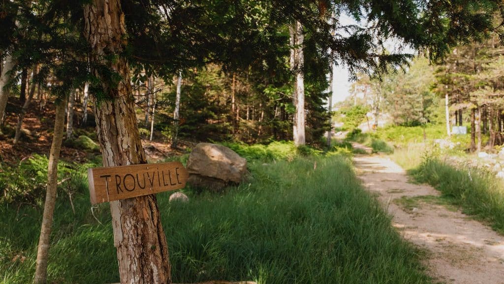 Treskilt med teksten "Trouville" ved en skogssti på Hankø.