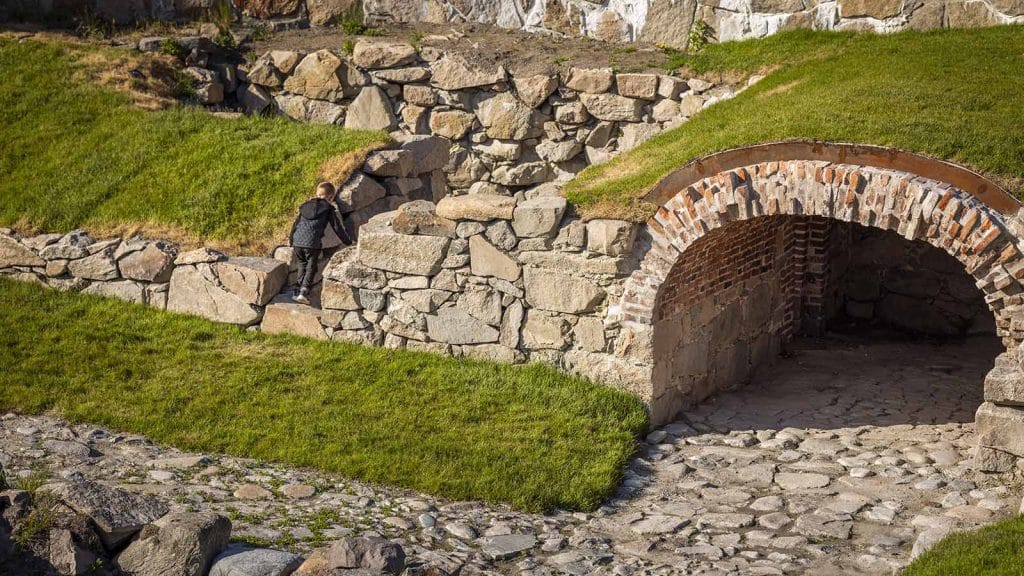Barn utforsker steinmurer og buet inngang i tårnet på Isegran.