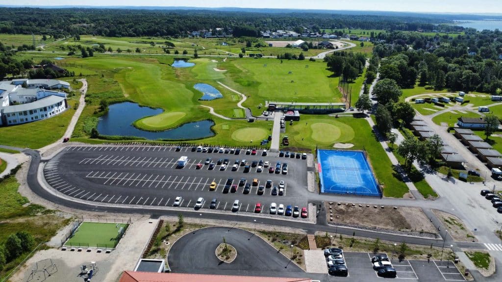 Luftfoto av parkeringsplass ved Brakkesletta/Kongsten, med golfbane, blå ballbane og campinghytter i bakgrunnen.